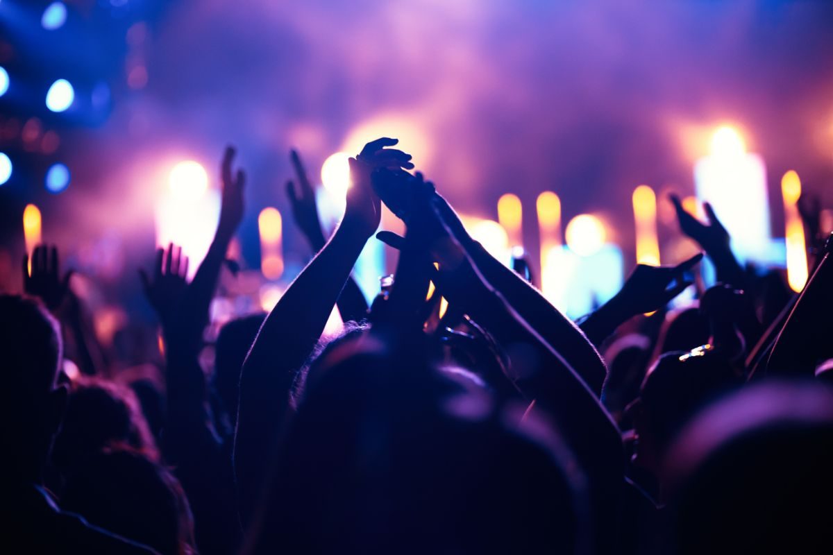 A crowd with hands raised at a nighttime concert