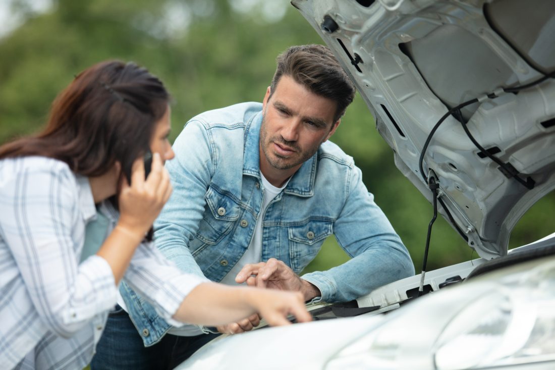 A couple looking under the hood of a car